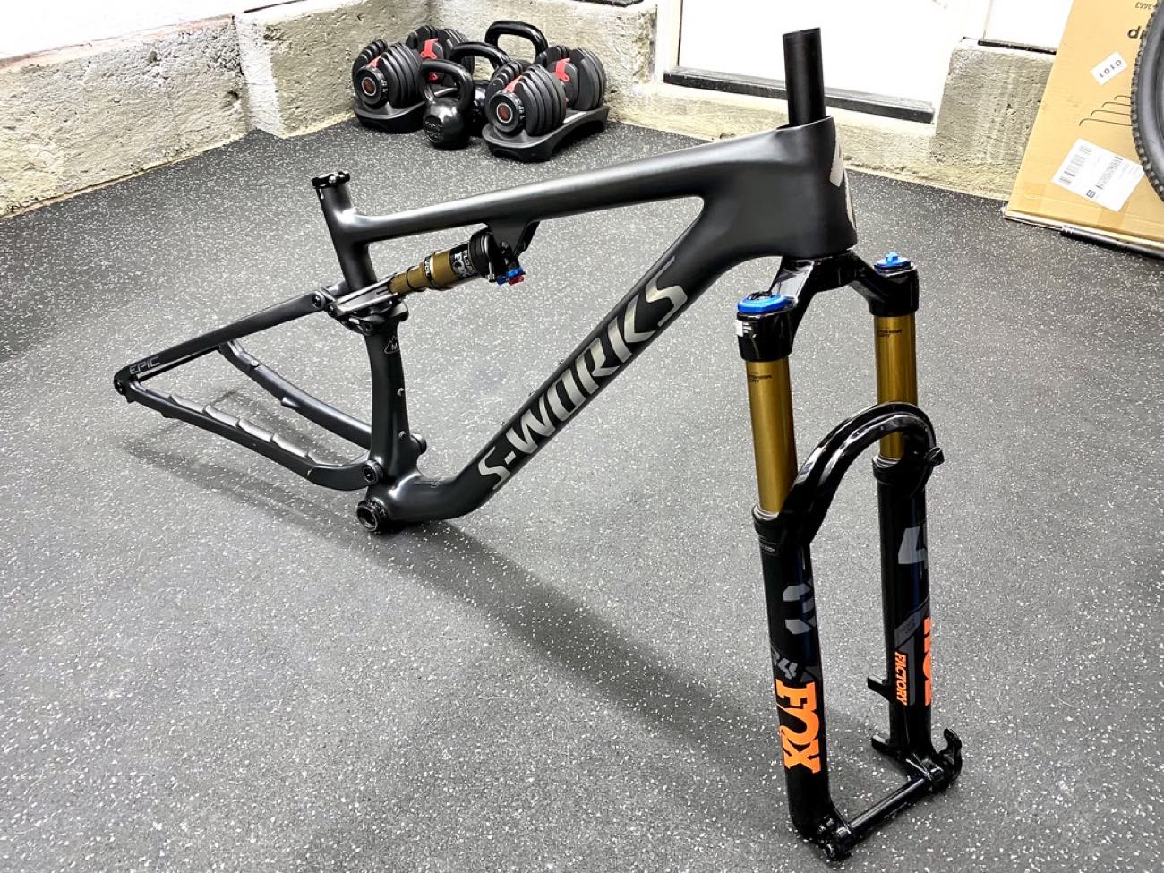 Bare full-suspension carbon frame with its rear shock beside a suspension fork