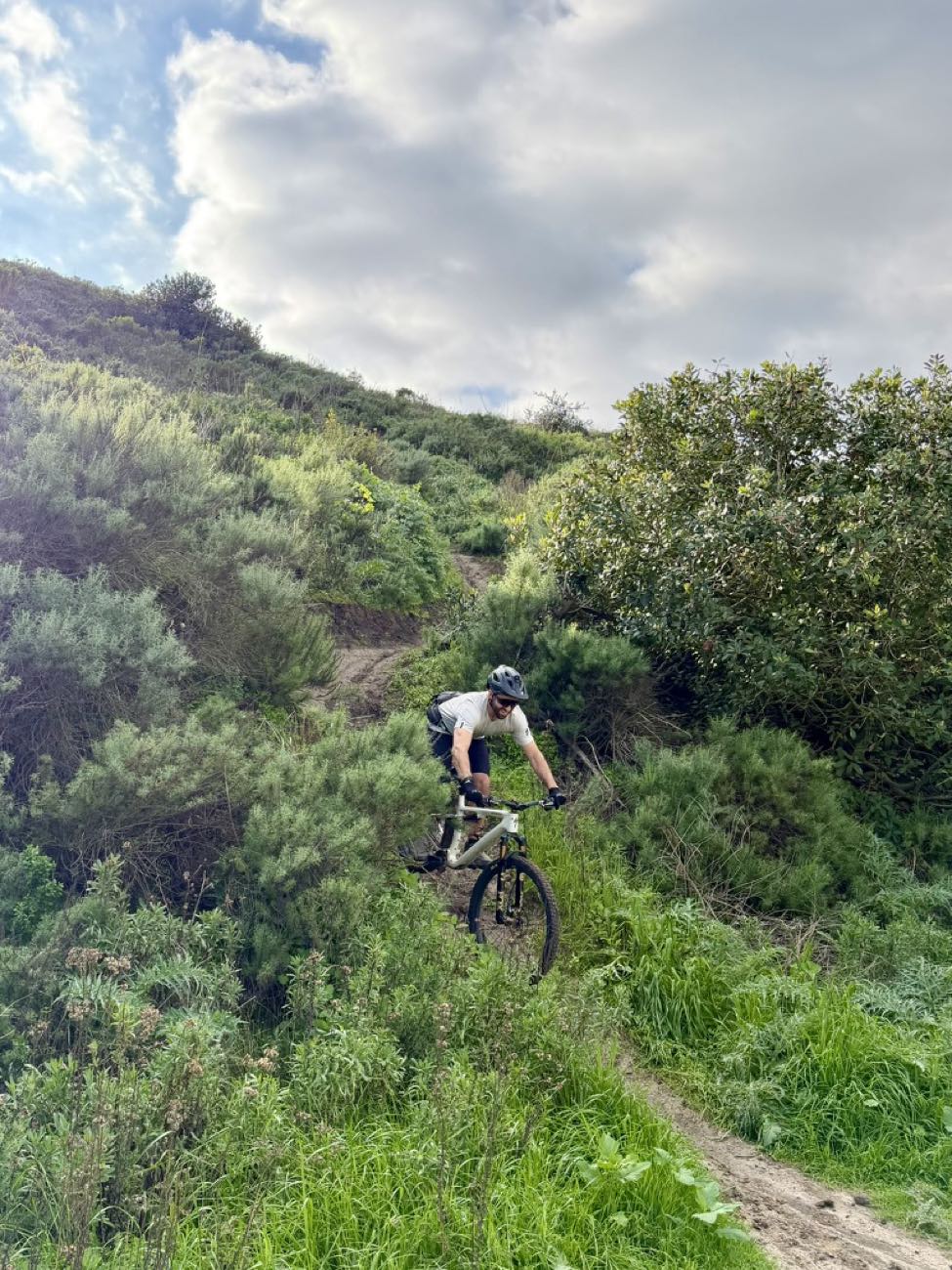 Rider dropping into a steep green hillside descent