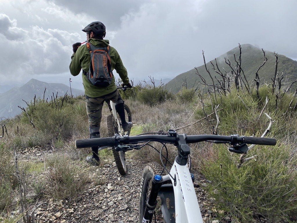 Rider with a hydration pack looking out from a high ridge