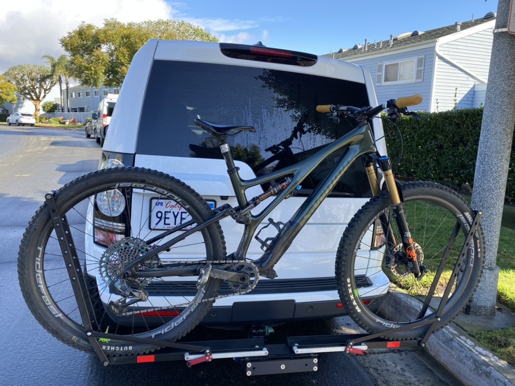Olive green Specialized Stumpjumper loaded on a 1UP USA platform hitch rack behind a white SUV