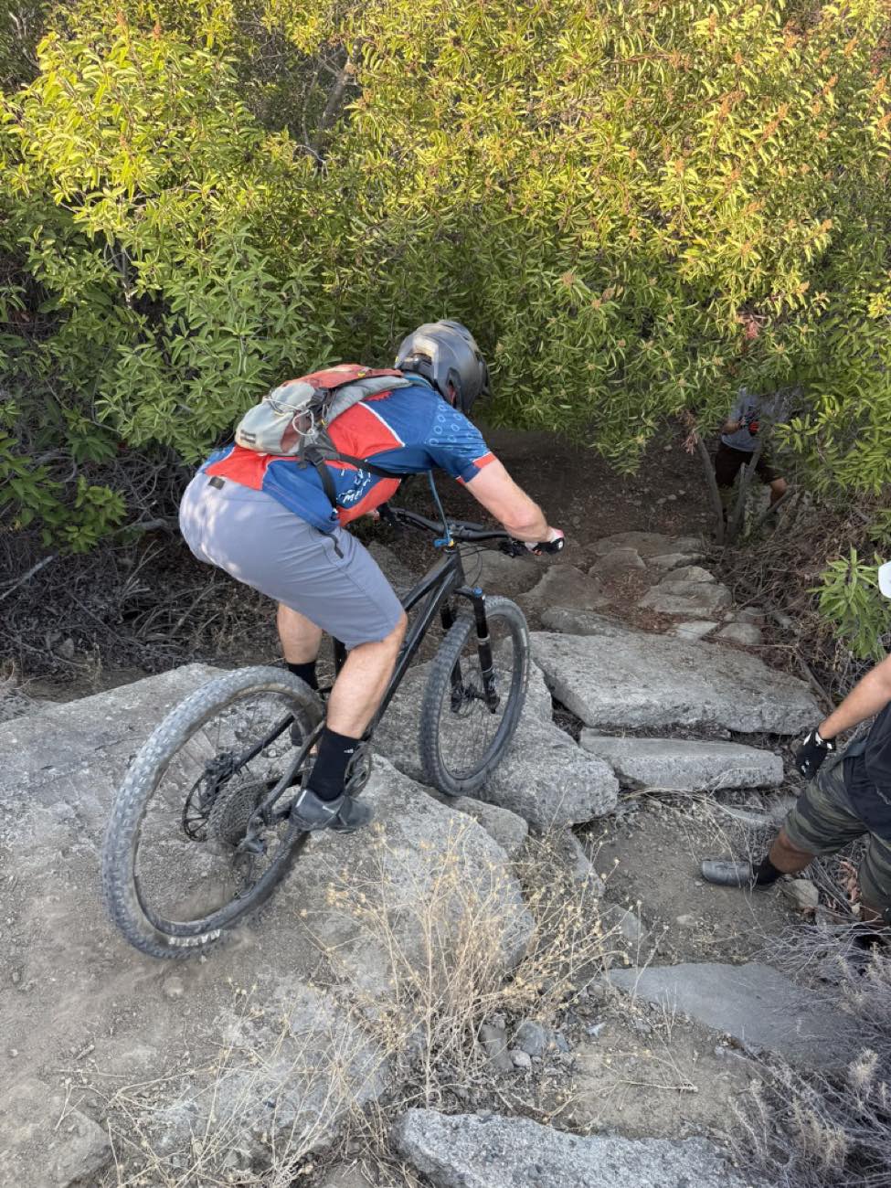 Rider dropping down a steep rock step on a technical descent