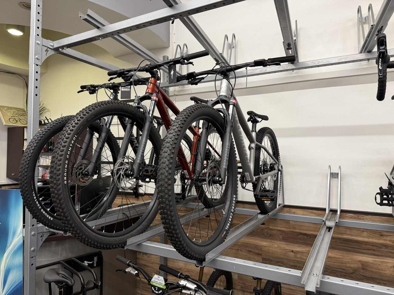 Two hardtail mountain bikes on an overhead shop display rack