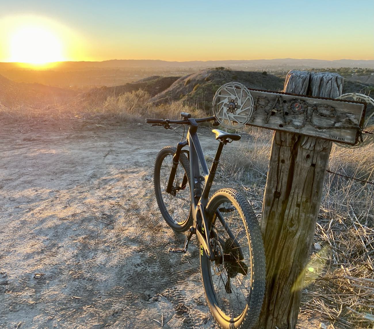 Mountain bike beside a wooden trail marker sign at sunset