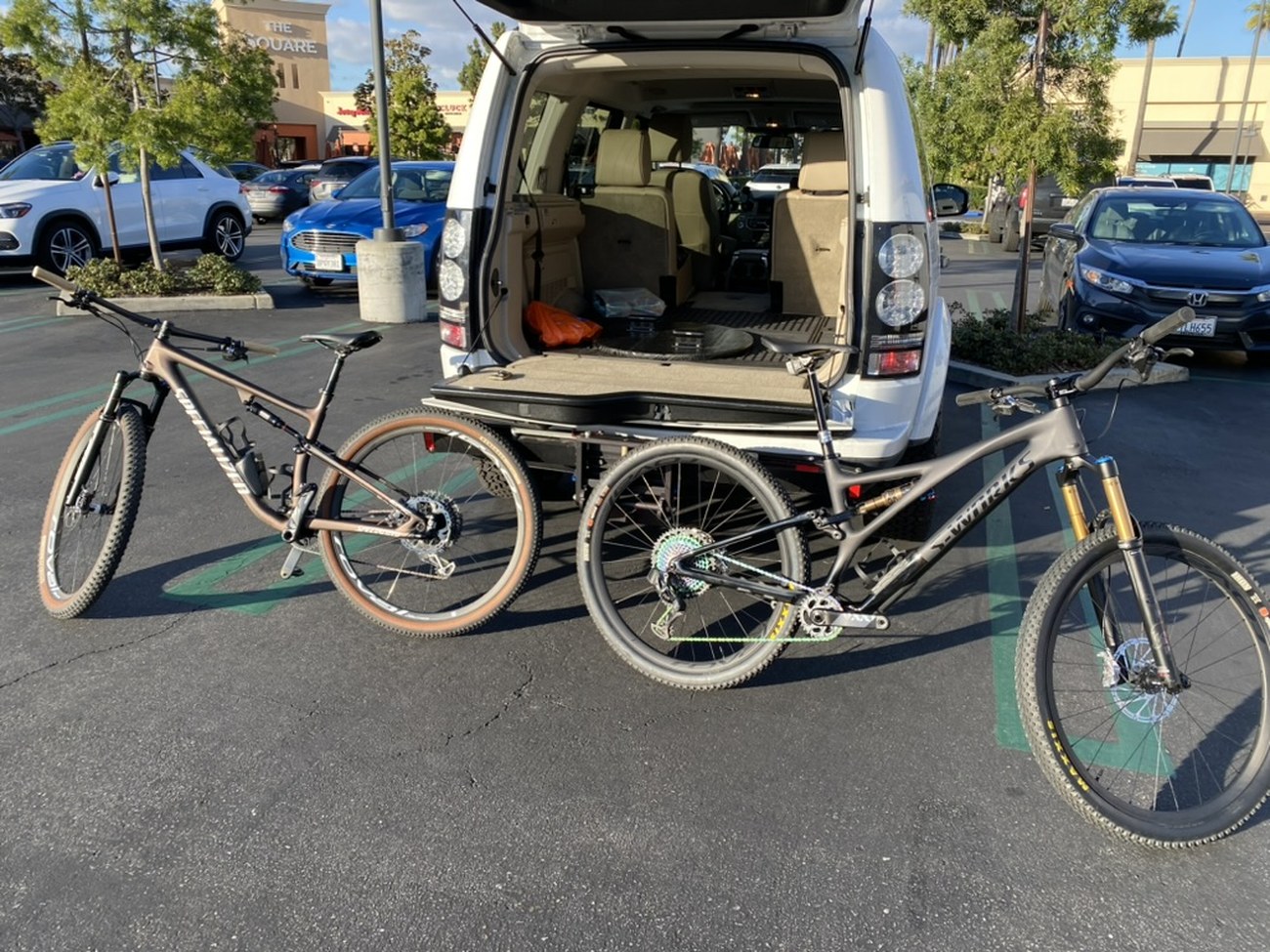 A cross-country bike and a trail bike side by side behind a vehicle